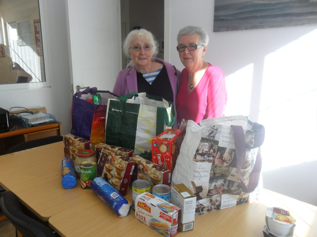 Pictured with some of the food for distribution are Help at Home volunteers Eileen Mayes (left) and Sheila Rowell.