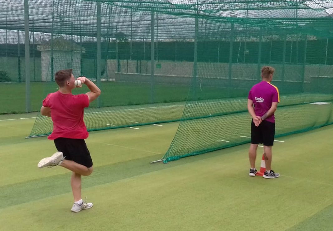 Connor Wood bowling, with Tommy Knowles umpiring, during training.